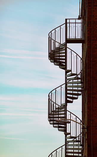 Spiral staircase beside an old industrial building.