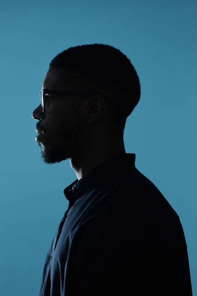 African American Man Wearing Glasses Side View Side view profile outline of African-American male silhouette against deep blue background isolated on dark stock pictures, royalty-free photos & images