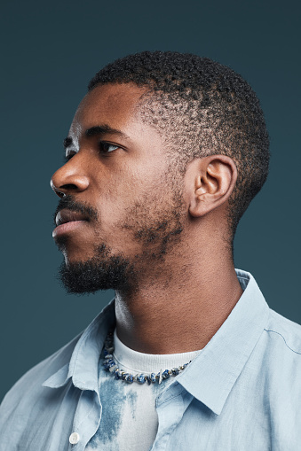 Vertical side view portrait of handsome African-American man against blue, focus on profile outline
