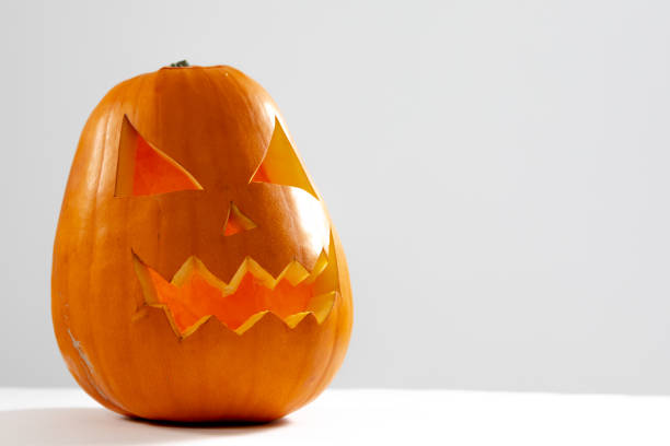 istock Composition of scary halloween carved orange pumpkin on white background 1347496621