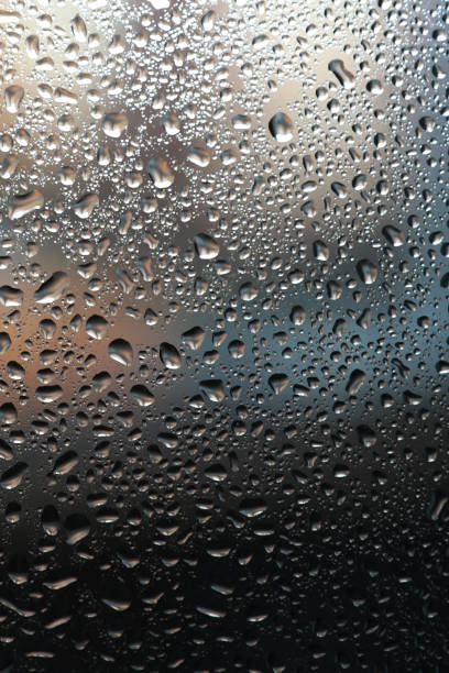 istock Close up of water drops on light tone background. Abstract black wet texture with bubbles on window glass surface or grunge 1347496625