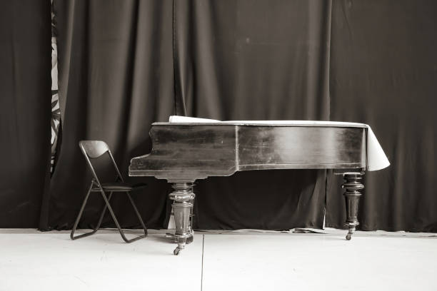 istock Old black grand piano on stage with curtain 1347496775