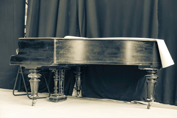istock Old black grand piano on stage with curtain 1347496781
