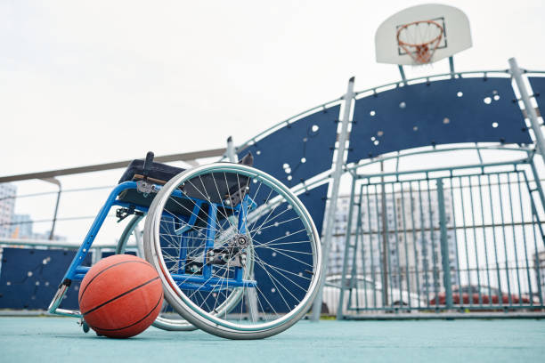Image of empty wheelchair with basketball ball on the outdoor sport ground