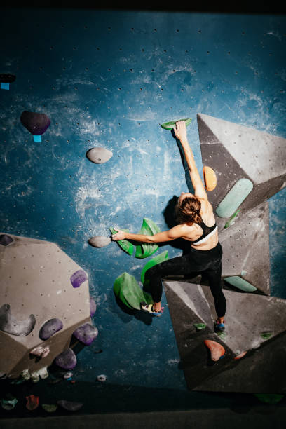 silna kobieta wspinająca się po ścianach głazów - wspinaczka skałkowa w pomieszczeniach - muscular build rock climbing mountain climbing women zdjęcia i obrazy z banku zdjęć