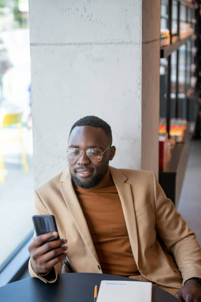 istock African man scrolling in smartphone by table in bookshop 1347501222
