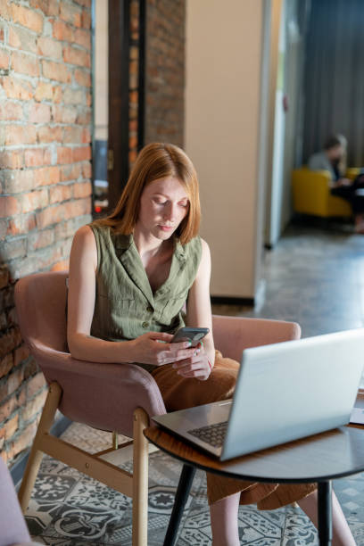 istock Young female scrolling in smartphone in front of laptop 1347501249