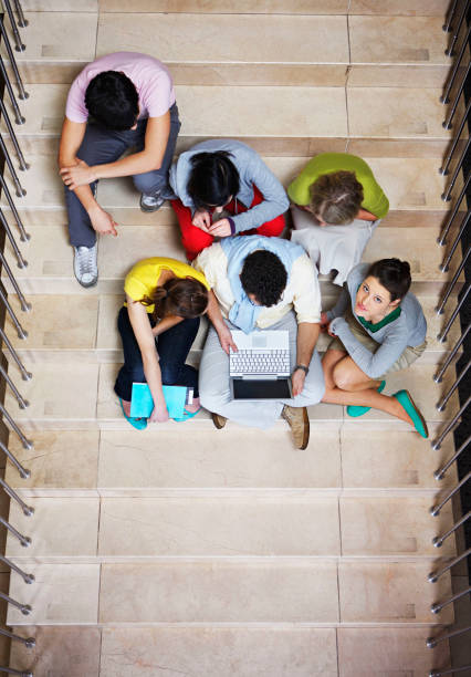 istock Overhead view of university students sitting on steps with laptop 1347501578