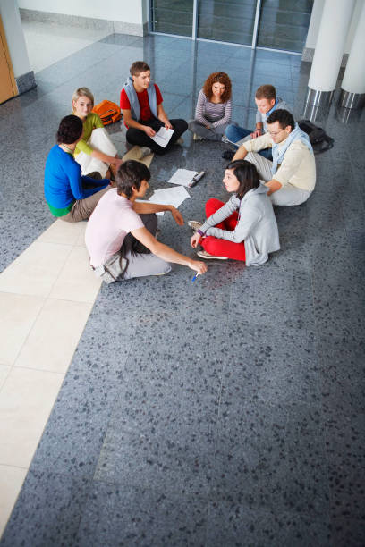 Multiracial group of young students studying together. High angle shot of young people sitting at the table and studying on laptop computer