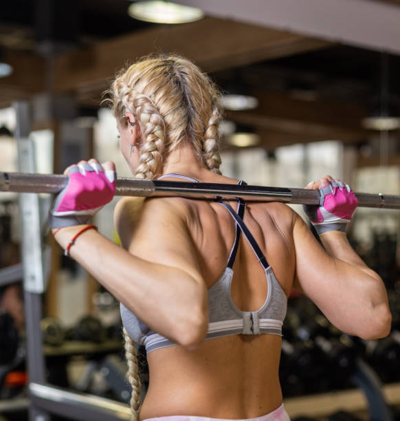 istock Rear view fit woman with barbell on her shoulders 1347501644