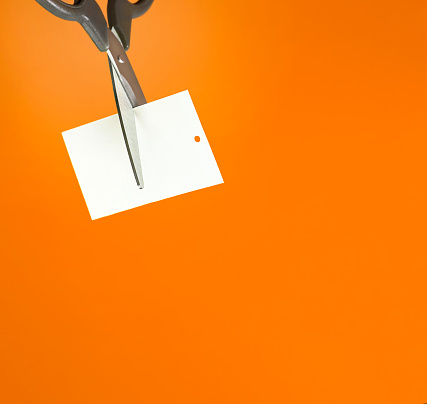 scissors cut the tag on orange background close up