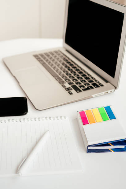 istock laptop, notebook, pen, colored stickers and phone on a white background. work from home. school online study. remote work. modern gadgets 1347503240