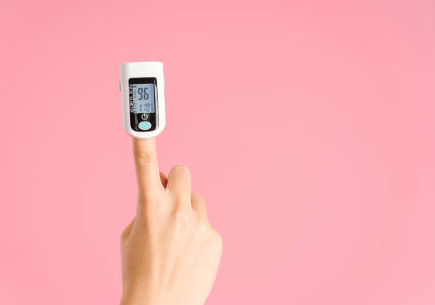 istock Female hand with pulse oximeter on index finger on pink background 1347503566