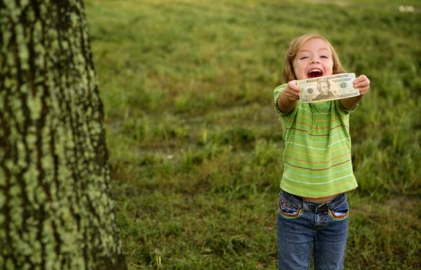 красивая счастливая маленькая девочка с долларовой купюрой - little girls childhood outdoors horizontal стоковые фото и изображения