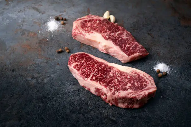 Premium quality marbled Japanese Wagyu beef on a dark stone background, fresh New York steak