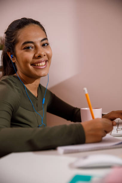 istock Young woman writing homework and smiling at camera 1347505209