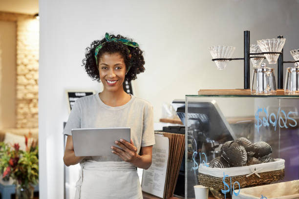 istock Smiling owner with digital tablet standing in cafe 1347505211