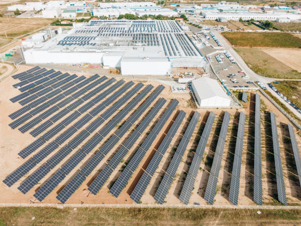 istock Solar energy farm next to industrial buildings 1347508113