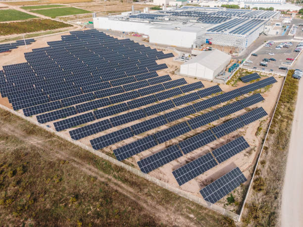 istock Solar energy farm next to industrial buildings 1347508221
