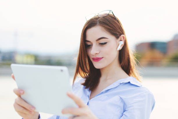 istock Young 20s woman with headset using tablet outdoors 1347513047