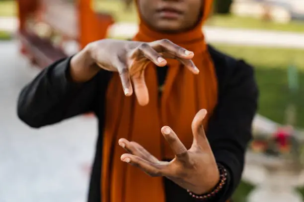 Close-up hands of black muslim woman at qigong chinese meditation and sport training outdoor. African girl is meditating outdoor near chinese arbor