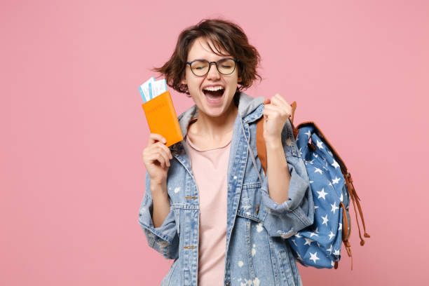 joyful young woman student in denim clothes glasses backpack isolated on pink background. education in high school university college concept. hold passport boarding pass tickets doing winner gesture. - shirt women pink jeans imagens e fotografias de stock