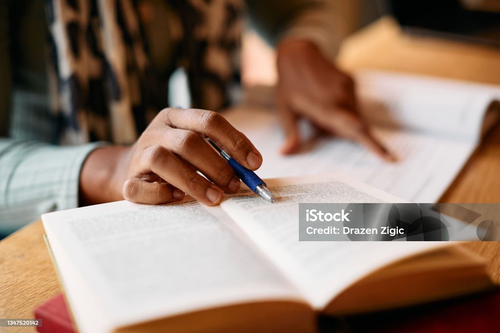 Close-up of African American woman doing some research in a library. Close-up of African American female student learning from books in a library. Studying Stock Photo