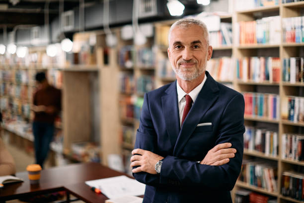 istock Portrait of confident mature teacher at university library looking at camera. 1347520439