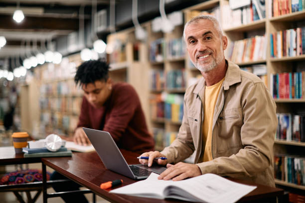 istock Happy mature man studying at university library and looking at camera. 1347520621