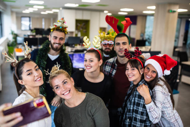 Coworkers taking selfies at the office Christmas party stock photo