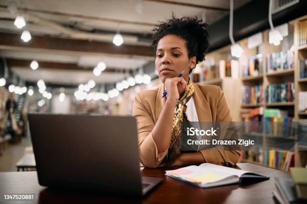 Mid Adult Black University Professor Working On Laptop In A Library Stock Photo - Download Image Now