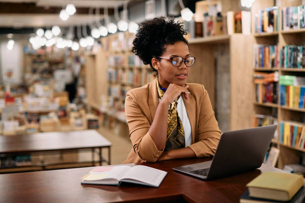 istock African American female professor using laptop while doing a research at university library. 1347520970