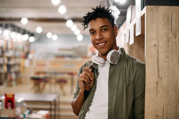 istock Young happy African American student standing in a library and looking at camera. 1347521625