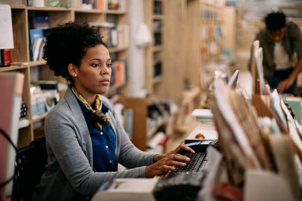afroamerikanerin, die desktop-pc benutzt, während sie in der buchhandlung arbeitet. - librarian stock-fotos und bilder