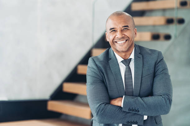 Portrait of a smiling middle aged businessman Smiling black mid-adult businessman standing with arms crossed mid adult stock pictures, royalty-free photos & images