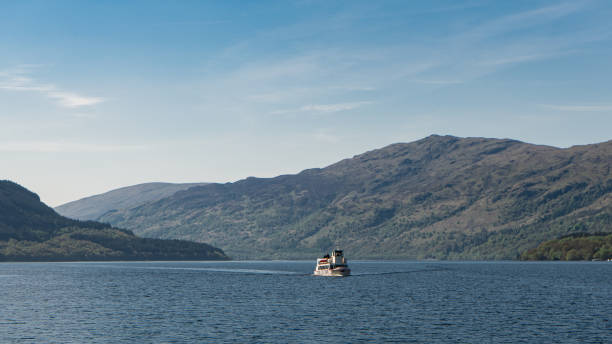 Boat in Loch Lomond with Mountains and trees in the background on a Sunny Day stock photo