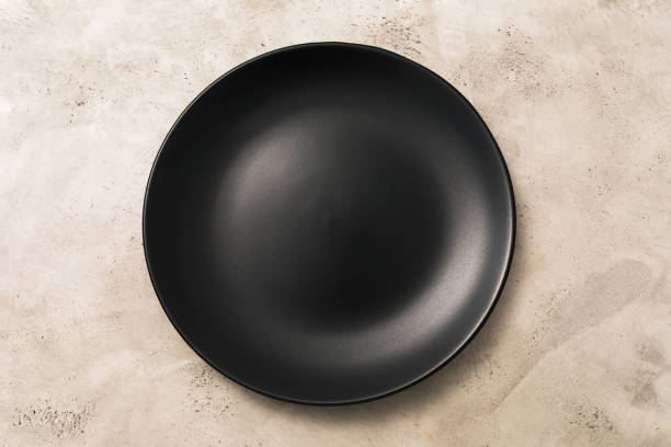 istock Empty black ceramic plate on light abstract background, top view, food background 1347523987