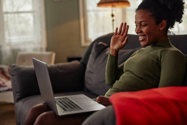 istock Black woman sitting on sofa and having video call 1347524638