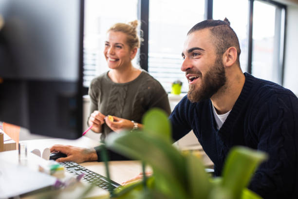 istock Two young adults relaxed an smiling while working at a casual office 1347529129
