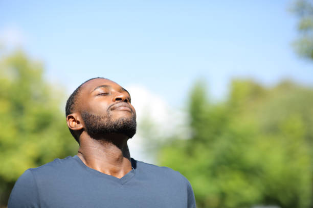 hombre de piel negra respirando en la naturaleza - exhalar fotografías e imágenes de stock