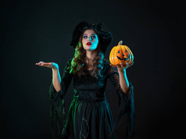 istock A young beautiful witch in a conical hat holds a Halloween pumpkin in her hands 1347531166