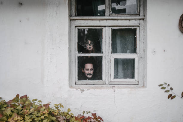 Disguised man and a woman looking through a broken window