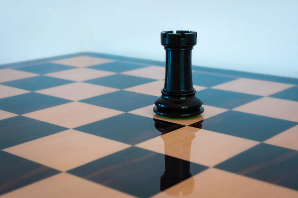 Black rook on a chess board Wooden chess piece. Black rook on a chess board, symbol of a tower of strength. chess rook stock pictures, royalty-free photos & images
