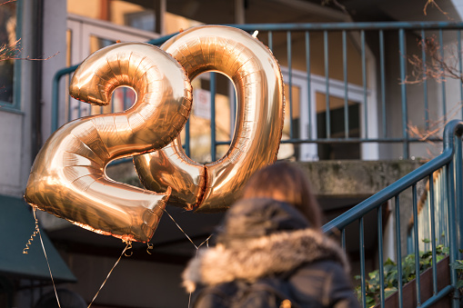 Seattle, Feb 20, 2020: One people with celebratory balloons with the number 20 on the Pike Place Market climb stairs late in the day.