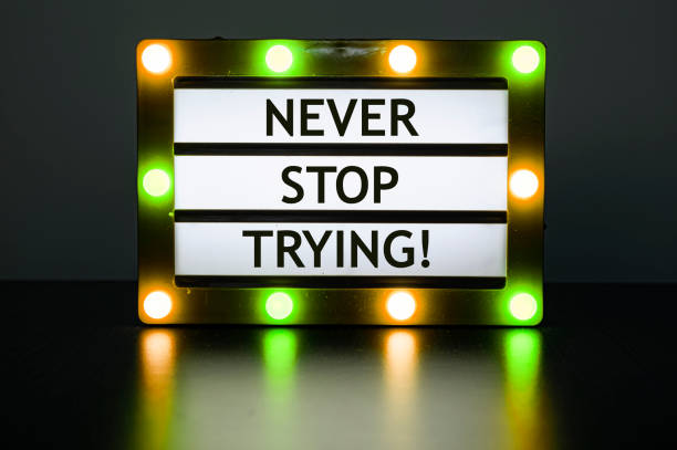 istock Lightbox with orange and green lights in dark room with words - never stop trying. 1347542607