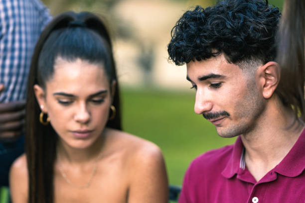 istock Two young people talking surrounded by other people in a park 1347543872