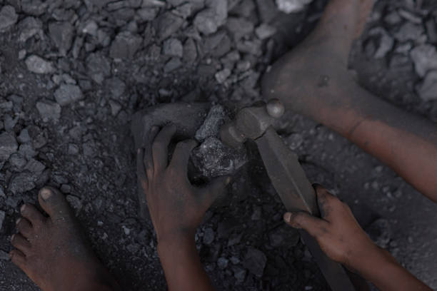 hard working little boy breaking coal with iron hammer and collecting coals closeup photo - lignite imagens e fotografias de stock