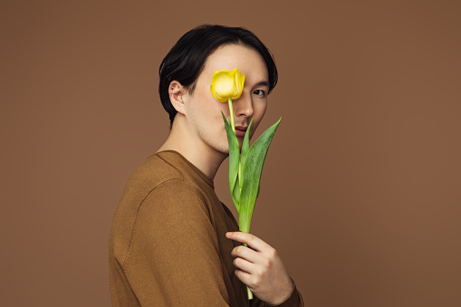 Emotional asian man holding a tulip