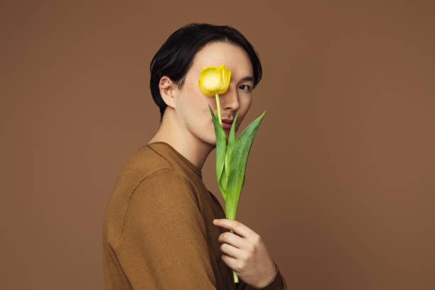 Emotional asian man holding a tulip Emotional asian man holding a tulip man flower stock pictures, royalty-free photos & images