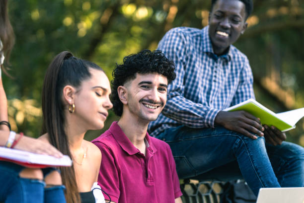 istock Modern smiling man sitting on a bench next to a multiethnic group of friends 1347549053